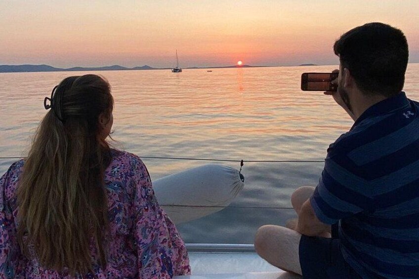 Un atardecer sobre un cuerpo de agua tranquilo, con un velero a lo lejos. 4