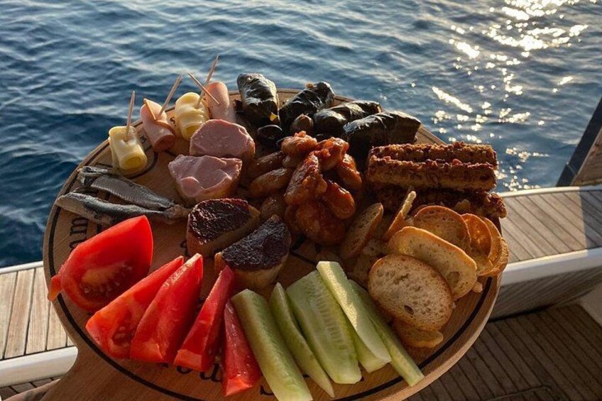 Una bandeja de madera con diversos alimentos, incluyendo tomates en rodajas, pepinos, pan y carnes. 5