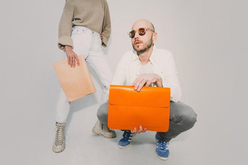 Twee personen met oranje en beige koffers. 1