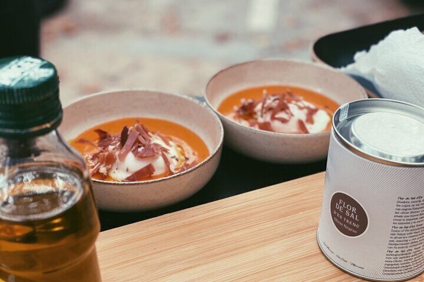 Two bowls of soup with a bottle of oil and a can of salt on a wooden table. 3