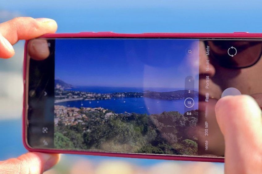 A smartphone displaying a coastal landscape with a clear sky. 3