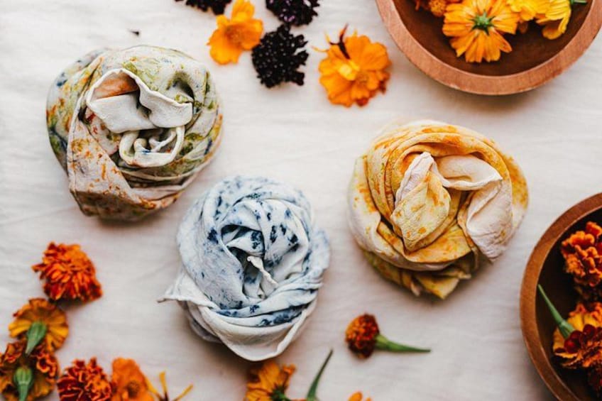 Three rolled-up cloths with floral patterns, surrounded by various flowers on a light surface. 4