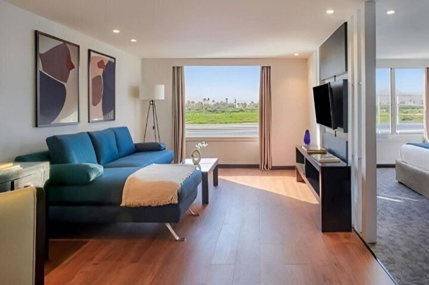 A modern living room with a sofa, a coffee table, a TV, and a view of the outdoors. 3
