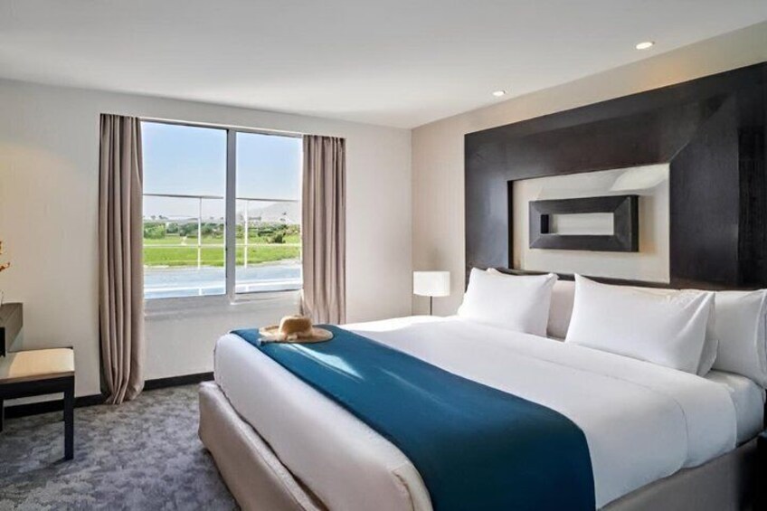 A modern hotel room with a large bed, a desk, and a view of the outdoors. 4