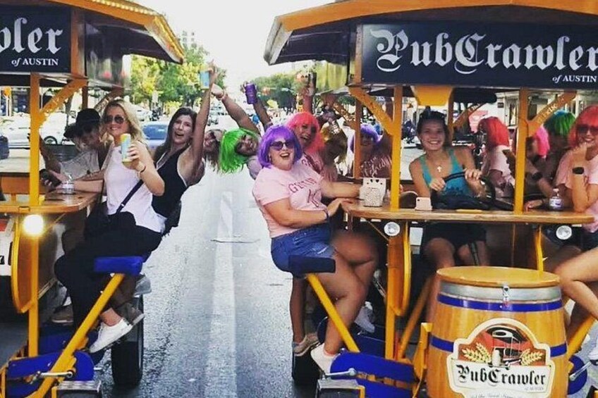 A group of people on a trolley with 'PubCrawler' branding, enjoying a ride. 2