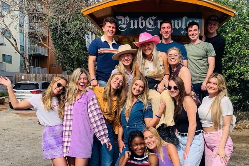 A group of people posing in front of a building with a sign that reads 'Pub Crawls.' 3