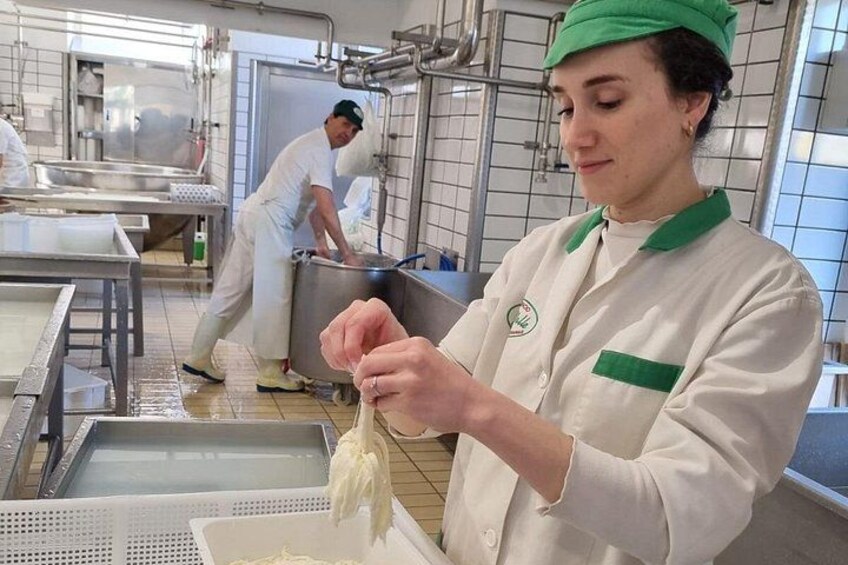Een persoon in een wit uniform met groene accenten bereidt eten in een professionele keuken. 1