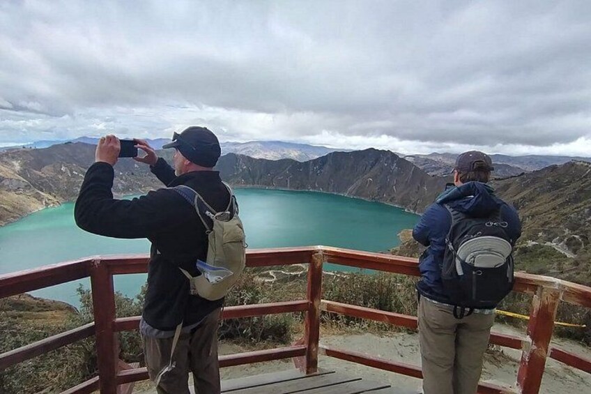Dos personas fotografiando un lago turquesa rodeado de montañas. 5