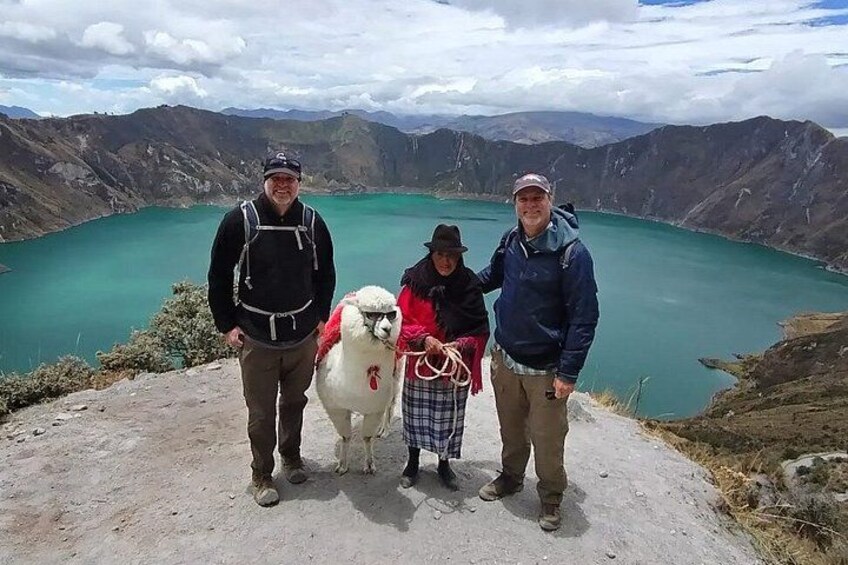 Tres personas de pie al borde de una montaña, con un lago al fondo. 4
