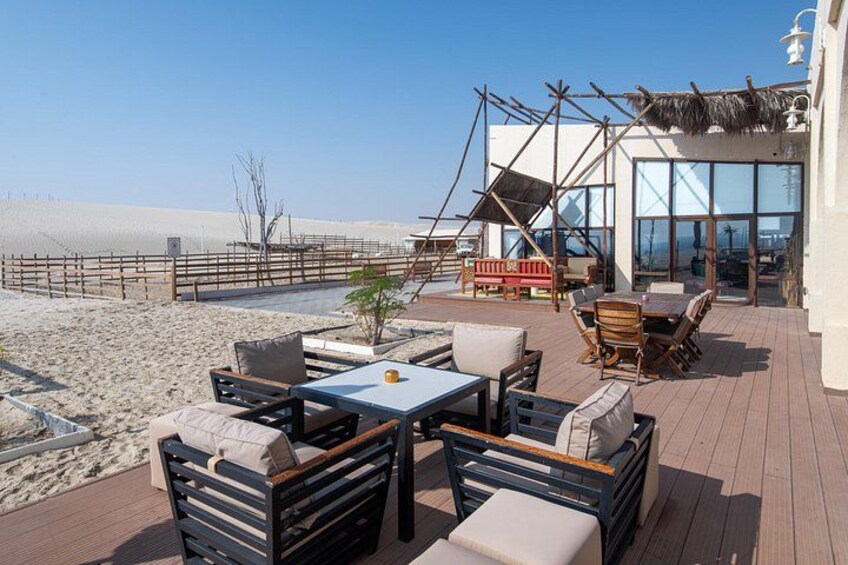 A beachside patio with outdoor furniture, a thatched-roof structure, and a view of the beach. 5