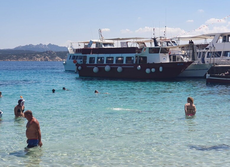 A boat docked at a marina with people swimming in the water. 3