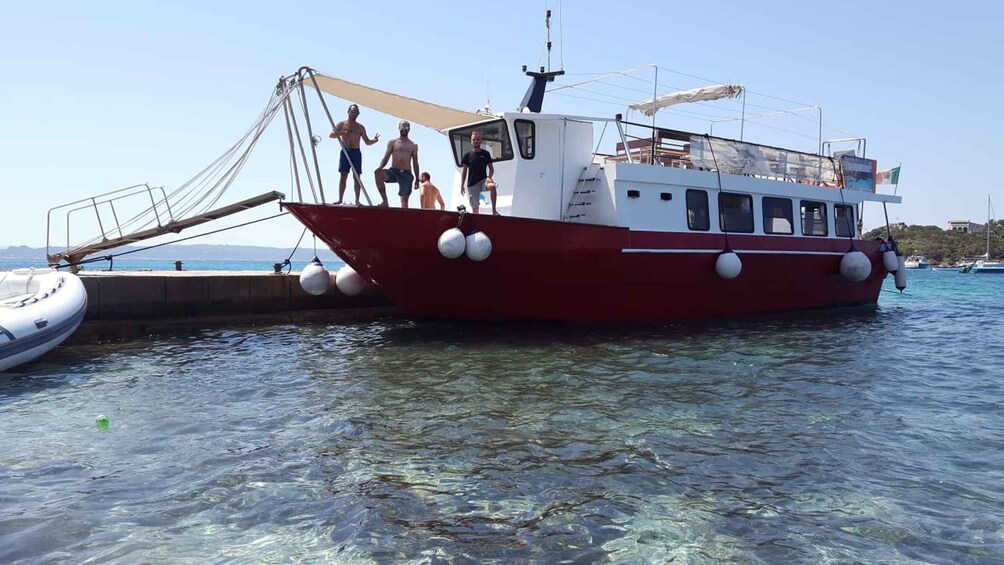 A red and white boat docked at a pier with people on board. 5