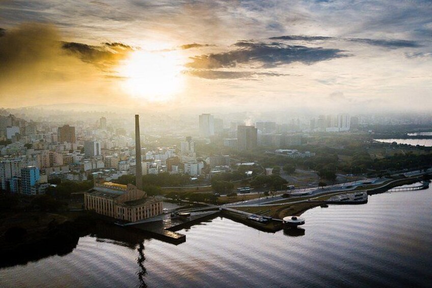 A cityscape with a river, a prominent building with a tall chimney, and a bridge. 5