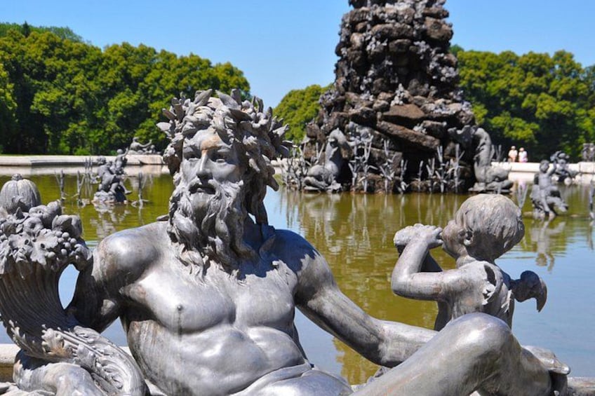 A statue of a muscular man with a beard, holding a child, surrounded by water and greenery. 5