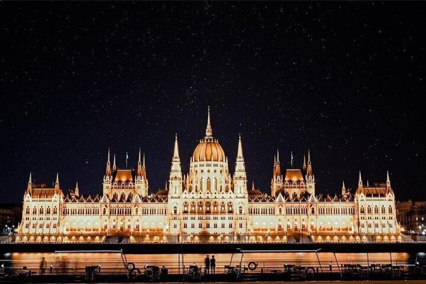A grand, illuminated building with multiple spires and domes, likely a government or historical building, at night. 5