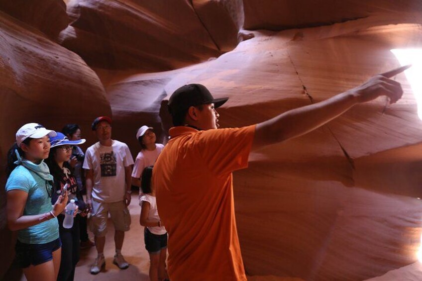 A group of people inside a canyon with a guide pointing out features. 3