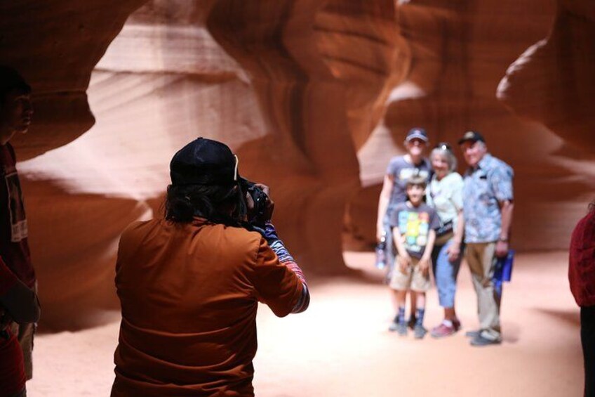 A person taking a photograph of a group of people in a canyon. 5