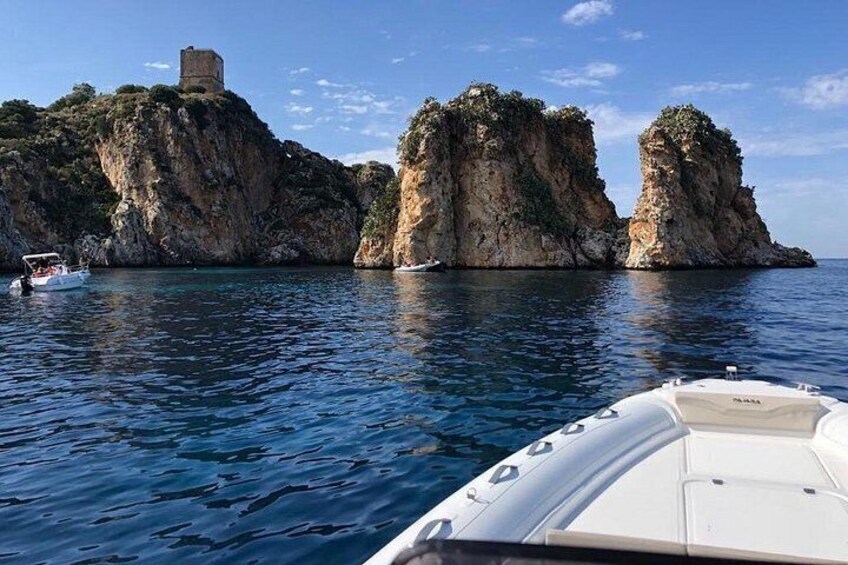 A boat on calm water with rocky cliffs and a tower in the background. 2