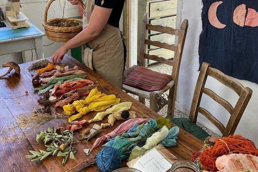 A person arranging colorful fabrics on a table with various tools and materials around. 2