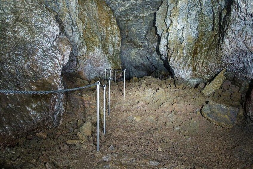 A cave interior with rocky walls, metal poles, and a rope barrier. 2