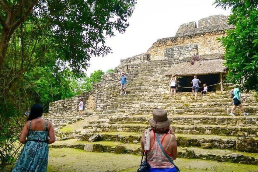 A group of people ascending stone steps towards a historical structure with a thatched roof. 3