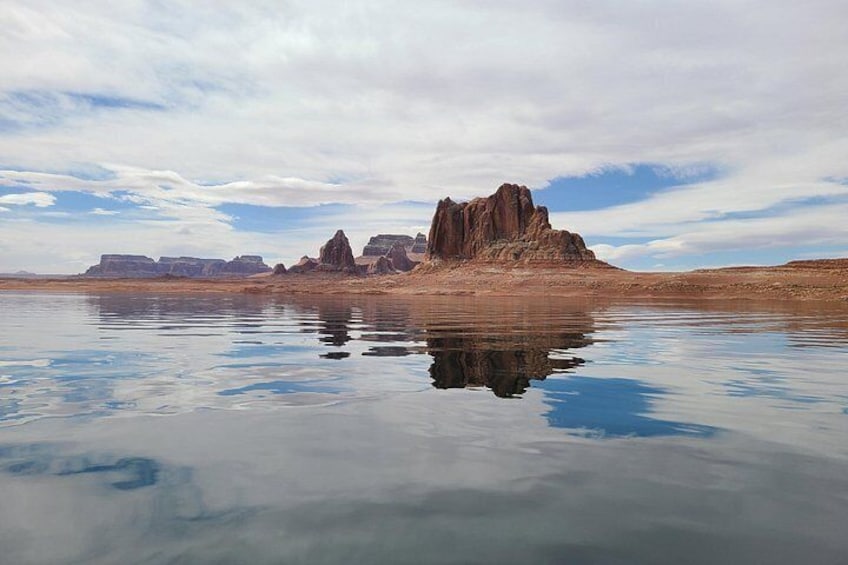 Un lac paisible aux eaux claires, où se reflètent les formations rocheuses, sous un ciel partiellement nuageux. 2