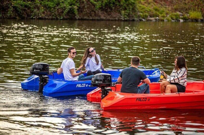 Four people on a lake in three small boats, one blue and two red, with "FALCO" written on them. 5