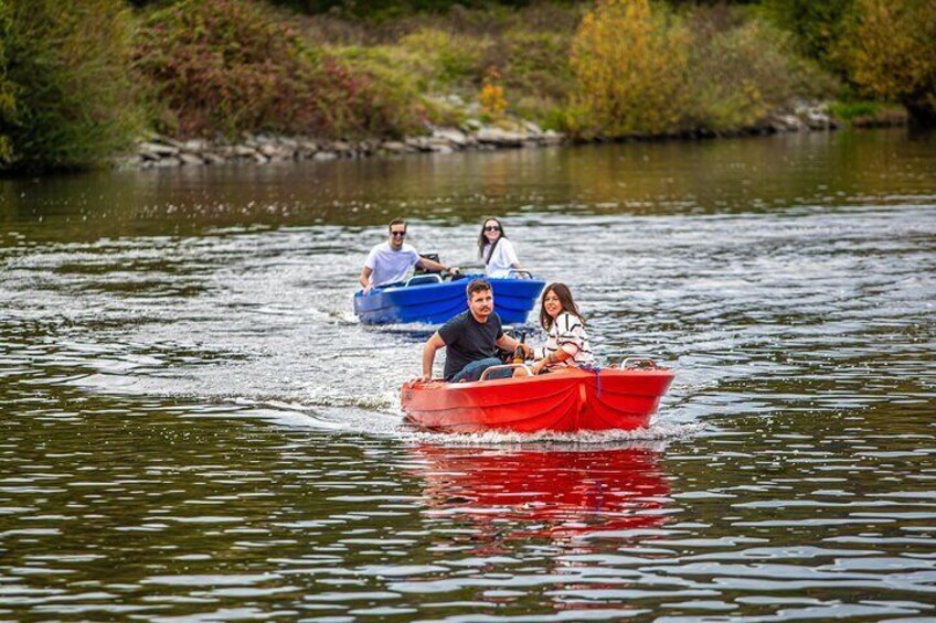 A red boat with three people on a river. 3
