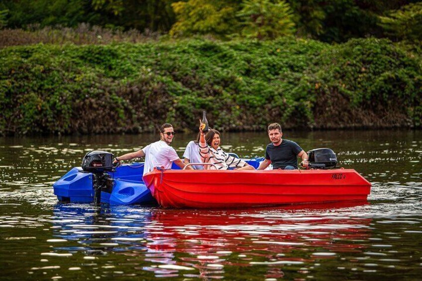 A red boat with three people on a calm lake surrounded by greenery. 2