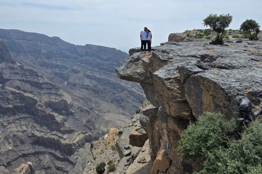 A person standing on a rocky cliff overlooking a vast canyon. 3