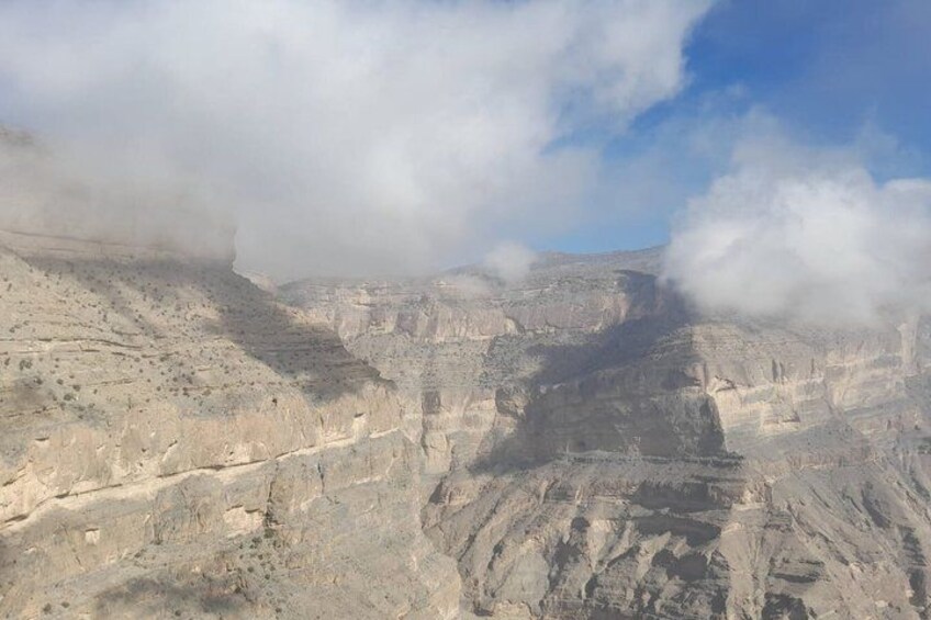 A canyon with layered rock formations and clouds. 2