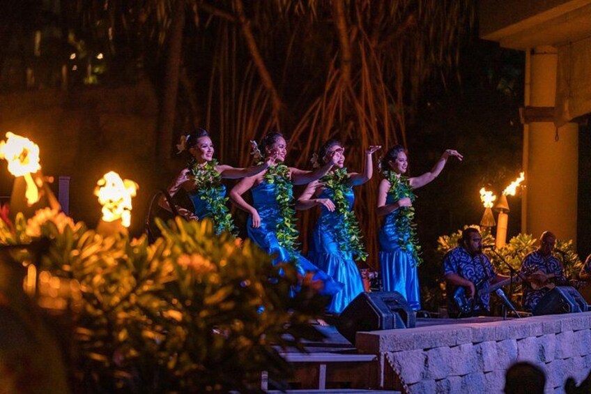 A nighttime outdoor event with people on a stage, lit by torches. 2