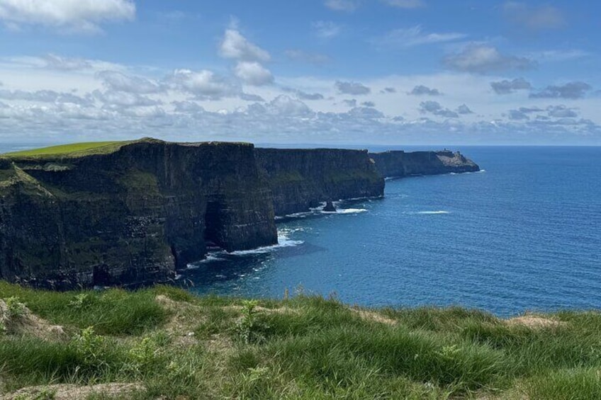 Eine Küstenklippe mit einem grasbewachsen Vordergrund und Blick auf den Ozean. 1