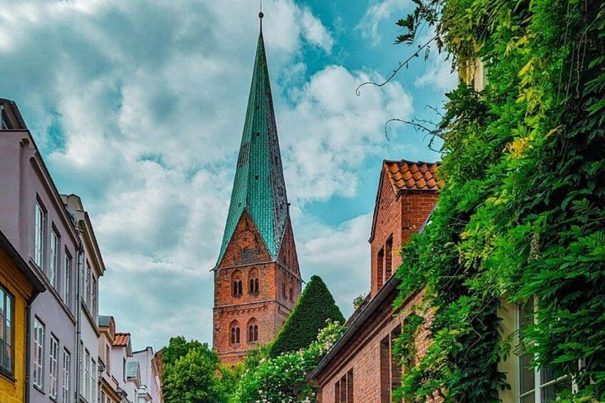 A church with a tall spire, surrounded by buildings and greenery. 2