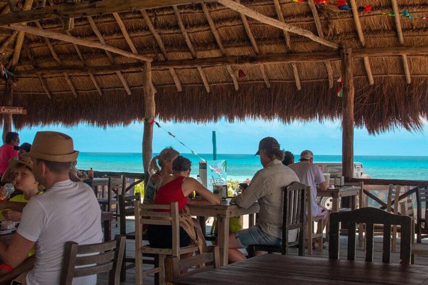 A beachside restaurant with thatched roofs and wooden tables. 3