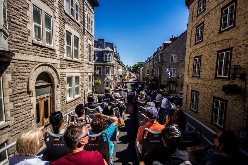 A group of people walking down a narrow street lined with historic stone buildings. 4