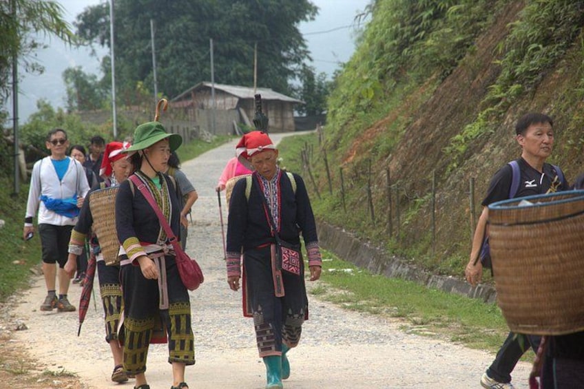 A group of people walking on a dirt path, some carrying baskets. 4