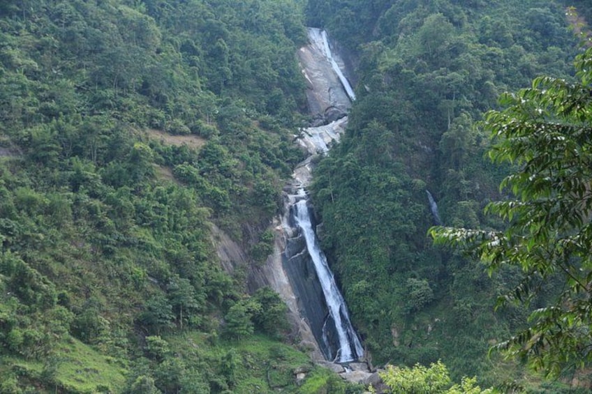 A waterfall cascading down a steep cliff surrounded by dense forest. 5