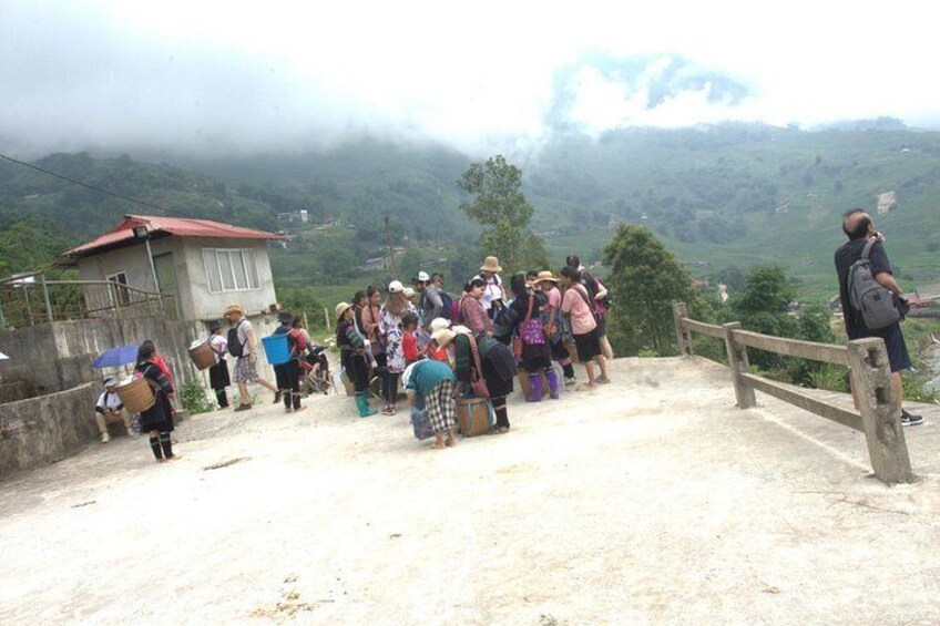 A group of people standing on a concrete platform overlooking a mountainous landscape. 5