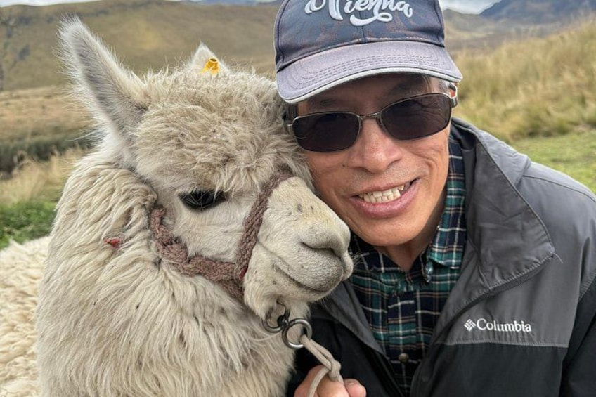 A person wearing a cap and jacket with the word 'Columbia' on it, standing next to a llama. 5