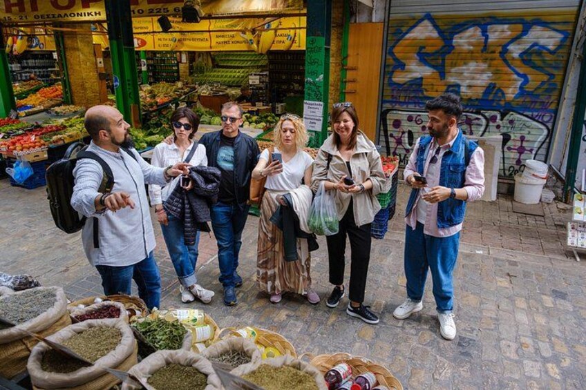 Un grupo de personas de pie en un mercado con varios productos expuestos al frente. 2