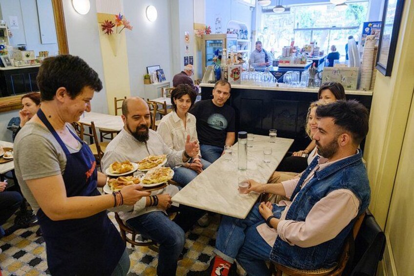 A group of people dining in a restaurant with a waiter serving food. 3