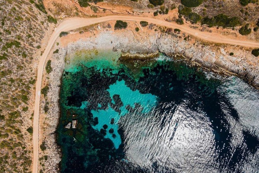 An aerial view of a coastal area with a road, rocky shoreline, and clear blue waters. 3