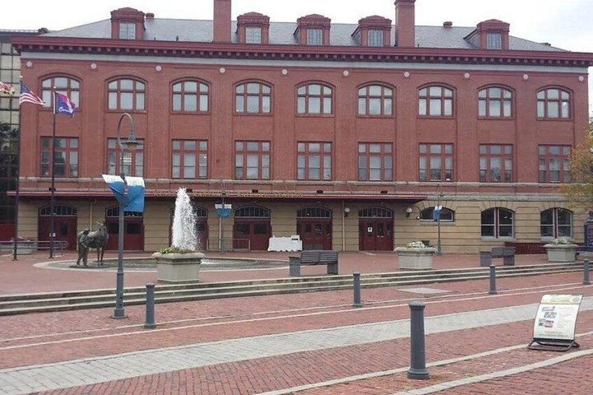 Un edificio de ladrillo rojo con ventanas de arco y una fuente en primer plano. 2