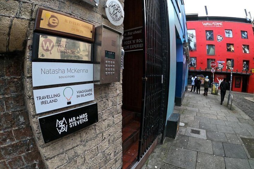 A street with multiple signs, including a red building with advertisements and a black door. 3