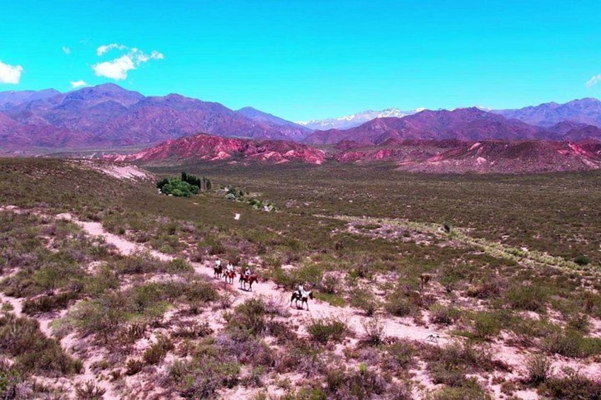 Paisaje desértico con montañas al fondo y un grupo de personas montando a caballo. 2