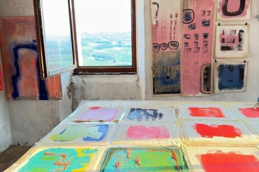 Una habitación con una mesa grande cubierta de muestras de pintura de colores y una ventana con vistas a un paisaje urbano. 5