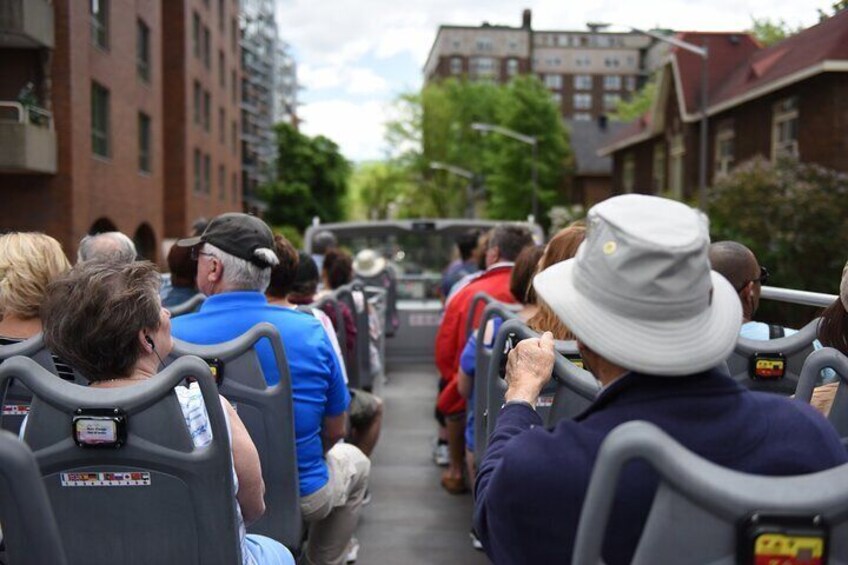 People seated on a bus, traveling down a street lined with buildings. 1