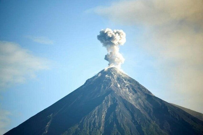 A volcano with a plume of smoke or ash rising from its peak. 3