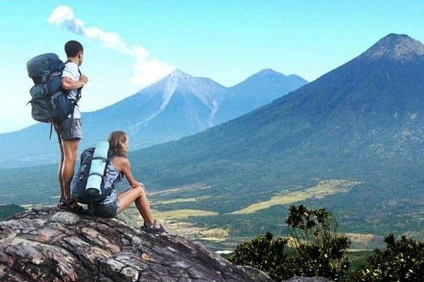 Two people on a rocky outcrop with a mountain in the background. 1
